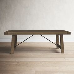 a wooden table sitting on top of a hard wood floor next to a white wall