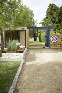 an outdoor archery area in the middle of a yard with grass and trees around it