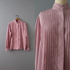 Vintage romantic essential minimalist secretary blouse in wisteria color. Pleated front, high neck, billowy sleeves. Silky polyester material. ⊰ Measurements: Fits like medium, large: 15" shoulders 42" bust 26" length 25" sleeves Tag: Dana Alexander Circa 1990s Condition: excellent! ⊰ Visit the shop: adriancompany.etsy.com ⊰ Instagram: @adriancovintage @the_veiled_ghost Feminine Pleated Blouse For Work, Elegant Pleated Blouse For Daywear, Elegant Spring Shirt With Pleated Details, Elegant Fall Blouse With Pintucks, Elegant Pleated Shirt For Spring, Elegant Pintucks Blouse For Fall, Spring Formal Pleated Top, Elegant Long Sleeve Lavender Blouse, Spring Vintage Blouse With Stand Collar