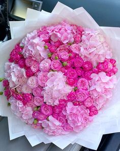 a bunch of pink flowers sitting on top of a white paper bag in the back seat of a car