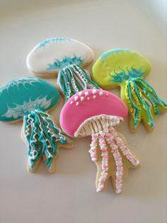 decorated cookies in the shape of jellyfishs on a white surface with blue, green and pink icing