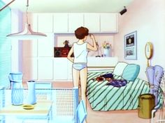 a woman standing at the end of a bed in a bedroom next to a sink