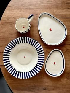 three plates and two cups sitting on top of a wooden table next to each other