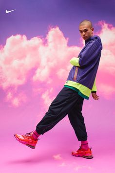 a man is standing in front of a purple and pink background with the word nike on it