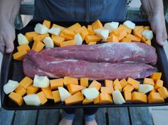 a person holding a tray filled with meat and vegetables