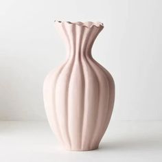 a pink vase sitting on top of a white table