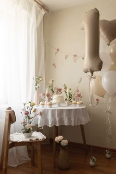 a table topped with cupcakes and balloons next to a window