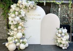 an arch decorated with white balloons and greenery