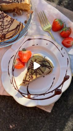 a slice of cheesecake on a plate with chocolate sauce and strawberries next to it