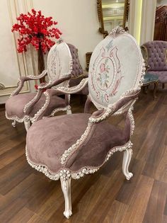 three chairs with ornate designs on them sit in a room next to a vase and mirror