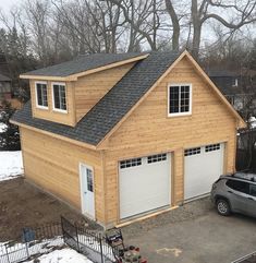 a car is parked in front of a two story garage with windows on the roof