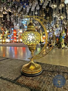 a golden lamp sitting on top of a rug in front of a store filled with hanging lights