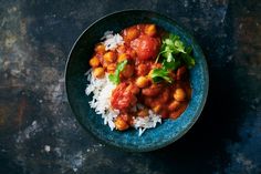 a blue bowl filled with rice and chickpeas on top of a black table