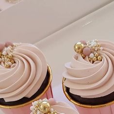 two cupcakes with pink frosting and gold decorations