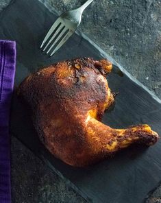 a cooked chicken sitting on top of a cutting board next to a fork