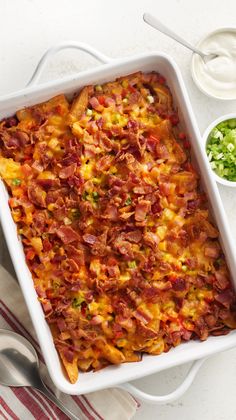 a casserole dish with bacon, cheese and other toppings on the side