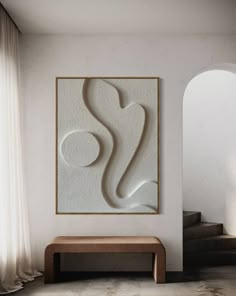 an abstract painting hangs on the wall next to a wooden bench in front of a window