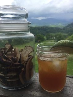 a glass jar filled with sliced mushrooms next to a drink