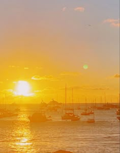 the sun is setting over boats in the water