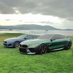 two cars are parked on the grass by the water