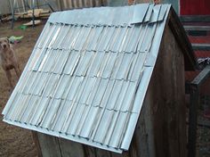 a dog is standing next to a small house with metal roofing on it's side