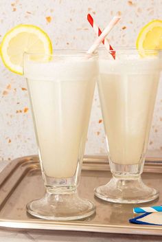 two glasses with lemonade and straws on a tray