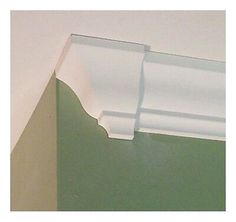 the corner of a room with green walls and white molding on the wall above it