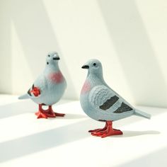 two small birds standing on top of each other in front of a white wall and shadows