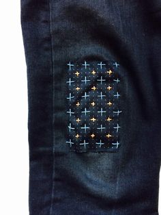 the back pocket of a pair of blue jeans with gold crosses on it and a white background