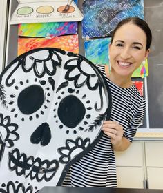 a woman holding up a paper plate with a skull on it