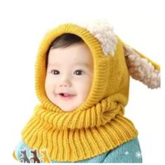 a baby wearing a yellow knitted hat and scarf with an animal on it's head