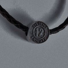 a close up of a leather cord with a metal button on the end that says district 12