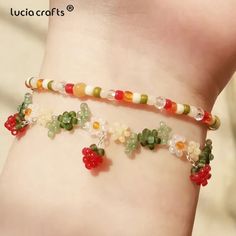 a close up of a person wearing a bracelet with fruit charms on it's wrist