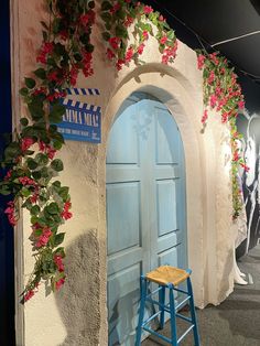 a blue stool sitting in front of a white building with flowers growing on it's side