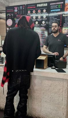 a man standing in front of a counter at a fast food restaurant with his back to the camera