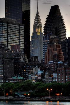 the city skyline is lit up at night, with skyscrapers in the foreground