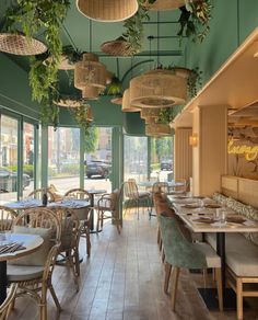 the interior of a restaurant with tables, chairs and plants hanging from the ceiling above