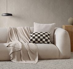 a white couch with a black and white checkered pillow sitting on top of it