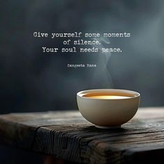 a cup of tea sitting on top of a wooden table with a quote above it