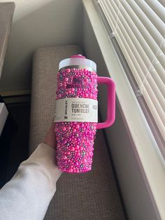 a person holding a coffee cup with pink and purple sprinkles on it