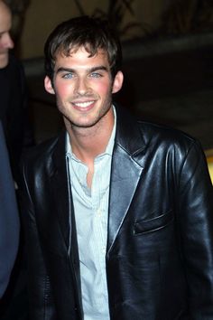 a man in a leather jacket smiling for the camera