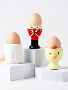 three eggs in the shape of an egg cup with a soldier's uniform on top