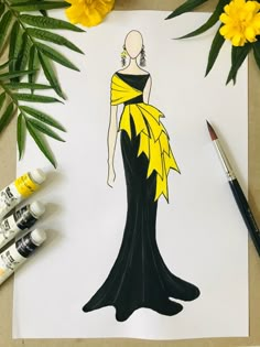 a drawing of a woman in a black and yellow dress on paper next to paintbrushes