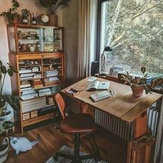 a room with a desk, chair and bookshelf next to a large window