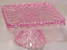 a pink glass cake stand on a white table