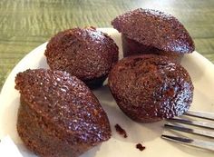 four chocolate muffins on a plate with a fork