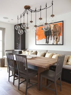 the dining room table is surrounded by gray chairs and an art piece on the wall