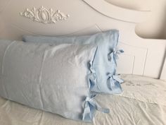 two light blue pillows on a white bed