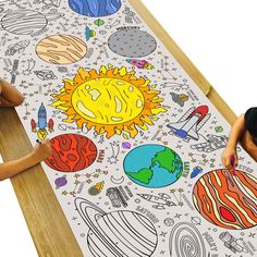 two children are sitting at a table with an image of the sun and planets on it