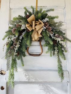 a wreath with pine cones and evergreens hangs on the front door